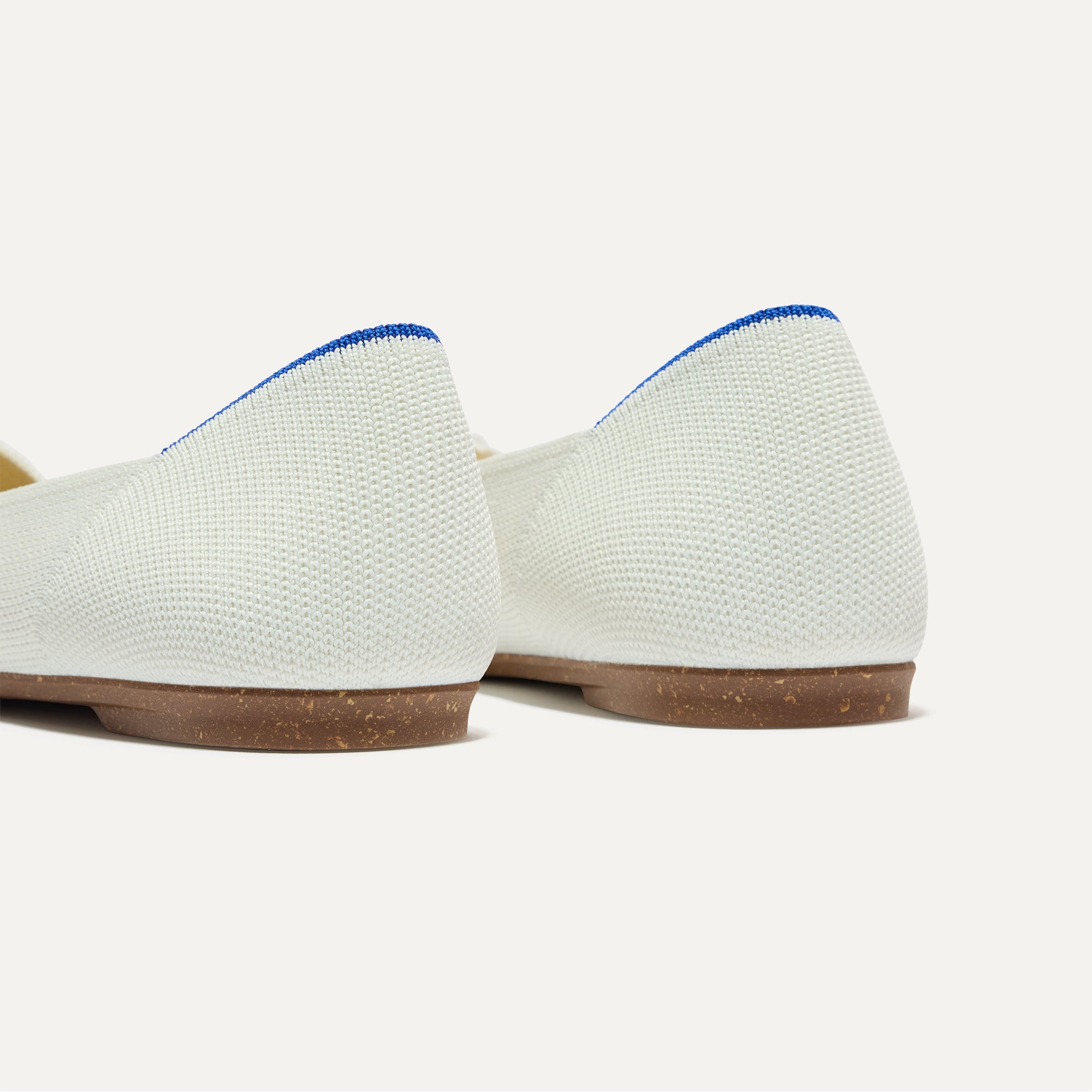 Close up of the heel of The Petal Point II in White, with Rothy's signature blue halo.