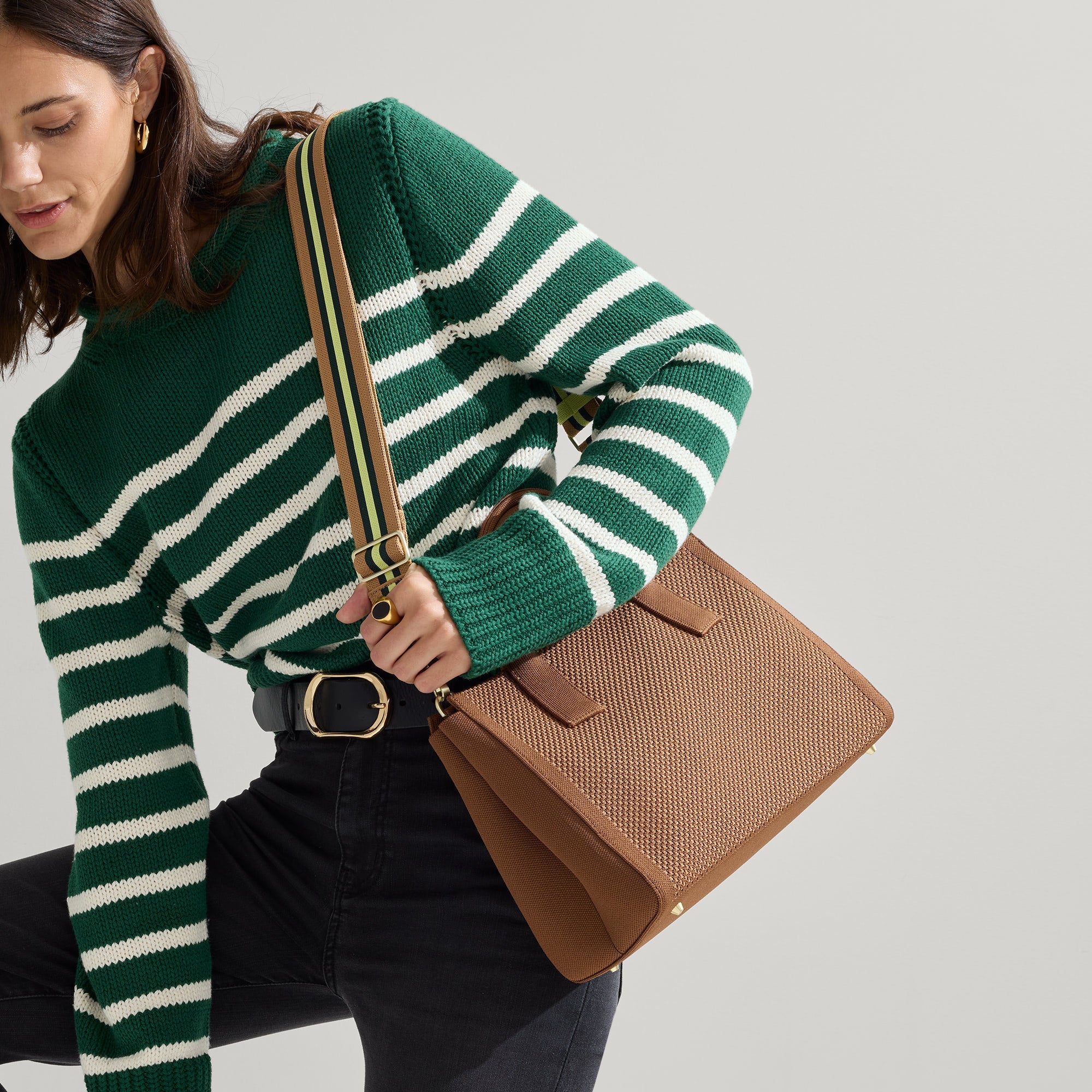 The Classic Handbag in Sierra Brown being carried by a model shown paired with The Crossbody Strap in Neon Pine Stripe.
