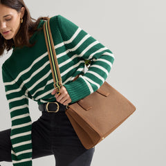 The Classic Handbag in Sierra Brown being carried by a model shown paired with The Crossbody Strap in Neon Pine Stripe.